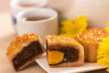Moon cakes with tea on bright wooden table and serving try, holiday concept of Mid-Autumn festival traditional food layout design, close up, copy space.