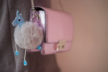 Small shiny purple women bag hanging with a fluffy ball unicorn keychain