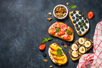 Sweet toast assortment with fresh fruit and berries on black.