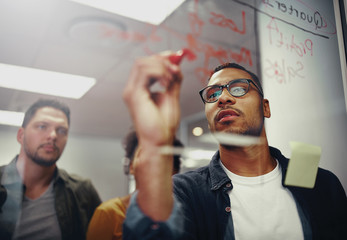 Young creative startup business people in meeting at modern office making plans on transparent glass