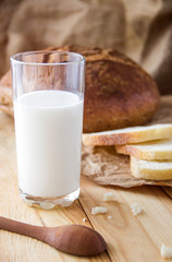 Glass of milk with slices of bread on a wooden table.Brown bread on the table