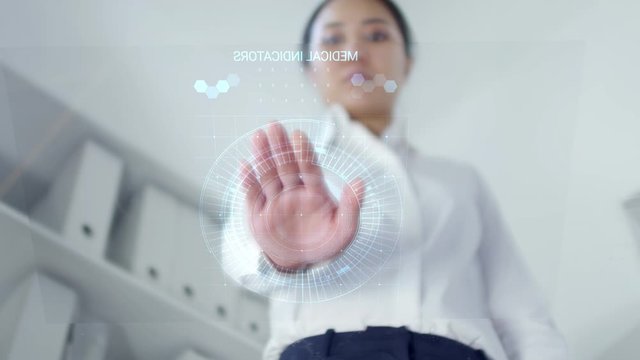 Low angle shot of woman putting hand on transparent touchscreen, scanning palm and reading AR medical information