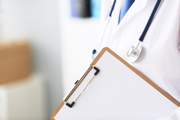 Close-up of clipboard with blank paper in medical doctor hand. Young male therapist is preparing for an interview with a patient.