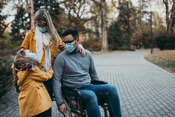 Fototapeta na wymiar Young family in protective mask outdoors in park. Air pollution concept.