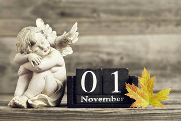 All Saints Day. Angel, wooden calendar and yellow autumn leaf - obrazy, fototapety, plakaty