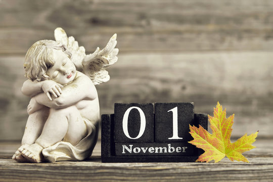 All Saints Day. Angel, wooden calendar and yellow autumn leaf