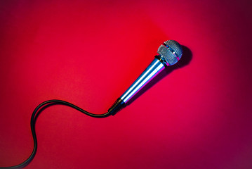 Silver microphone on a red background, with a black cord.