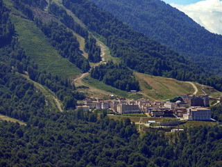 Fototapeta na wymiar ski resort hotels surrounded by green forest in a mountain valley at the foot of the high Caucasus mountains on a summer sunny day