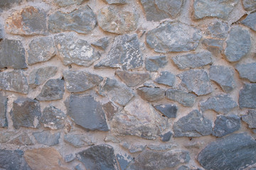 Background of natural stone. Large parts of the wall are flooded with concrete. Gray stone wall background.
