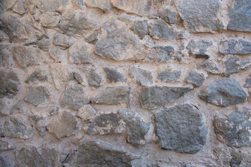 Background of natural stone. Large parts of the wall are flooded with concrete. Gray stone wall background.