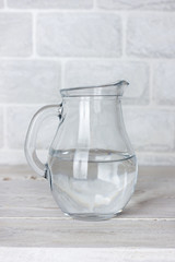 Dishes. Glass jug with water on a white wooden table