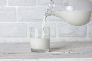 Dishes. Glass cup and jug with milk. Milk is poured from a jug.