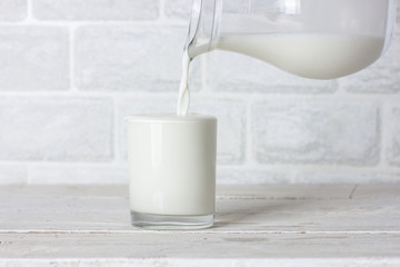 Dishes. Glass cup and jug with milk. Milk is poured from a jug.