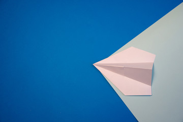White, small, paper plane on a blue background.
