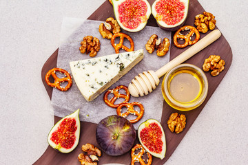 Cheese platter (board) with blue cheese, honey, walnuts, figs, pretzels