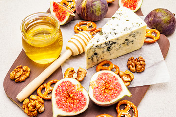 Cheese platter (board) with blue cheese, honey, walnuts, figs, pretzels