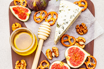 Cheese platter (board) with blue cheese, honey, walnuts, figs, pretzels