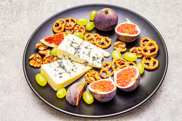 Cheese plate with blue cheese, walnuts, figs, grapes, pretzels