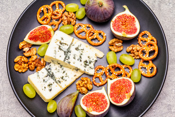 Cheese plate with blue cheese, walnuts, figs, grapes, pretzels