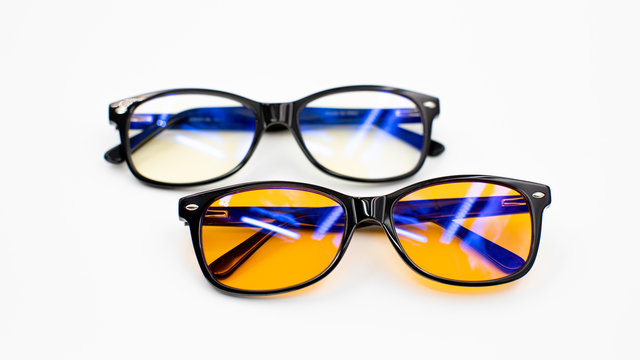 Isolated image of two blue light blocking glasses (day and evening, yellow/orange lenses) on a white background - health, good sleeping and wellness concept for melatonin and circadian rhythm