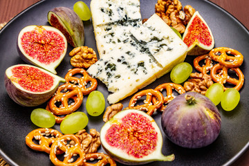 Cheese plate with blue cheese, honey, walnuts, figs, grapes, pretzels