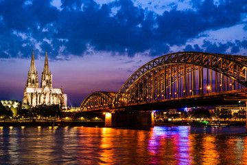 Beautiful night landscape of the Cologne, Germany with gothic cathedral, railway and pedestrian Hohenzollern Bridge and reflections over the River Rhine