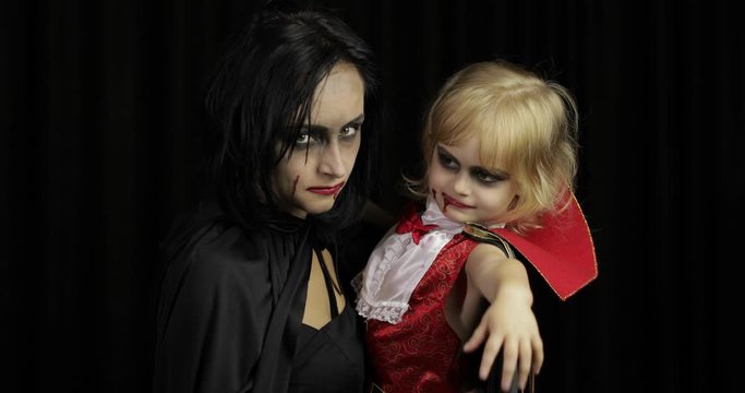 Woman and child dracula. Halloween vampire make-up. Kid with blood on her face
