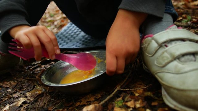 Camping lunch concept. Child eats porridge.