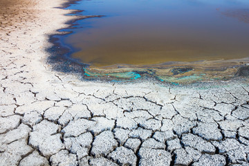 Heat, drought, disaster, saline soil, dry riverbed, blue sky reflected in the remnants of water....