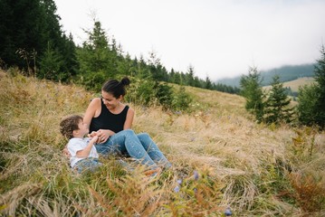 Naklejka na ściany i meble Young mom with baby boy travelling. Mother on hiking adventure with child, family trip in mountains. National Park. Hike with children. Active summer holidays. Fisheye lens