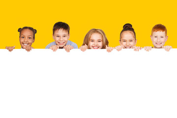 Happy children with empty board, yellow background