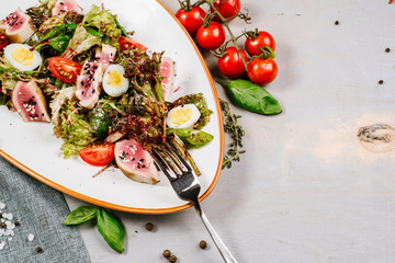 Tasty fresh salad with meat and vegetables on the wooden background