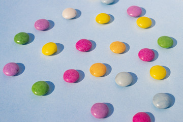 Blue background with multi-colored dragees scattered on the surface