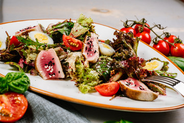 Tasty fresh salad with meat and vegetables on the wooden background