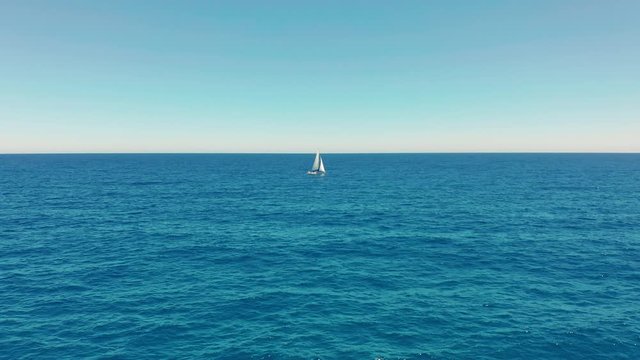 Sailboat in the ocean. White sailing yacht in the middle of the boundless ocean. Aerial view.