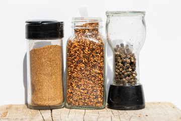 Three jars with spices of different grinding on a white backgrou