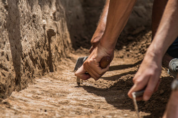 Archaeologists excavating with trowels 