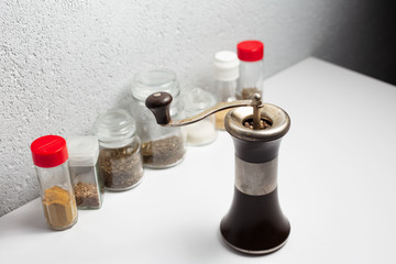 Ancient pepper mill near another seasonings on white background.