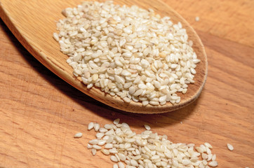 Organic natural sesame seeds on wooden spoon, healthy food background