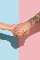 Closeup shot of human holding hands isolated on blue-pink studio background. Concept of human relations, friendship, partnership, family. Copyspace.