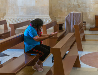 Believer sits on a bench and prays in the central hall in the catholic Christian Transfiguration...