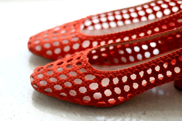 Trendy red mesh shoes, on marble background. Selective focus.