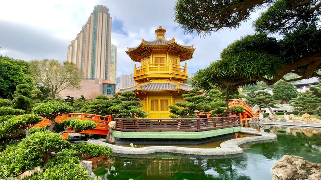 Goldene Pagode mit Hochhäusern von Diamond Hill an See in Nan Lian Garden in Hongkong