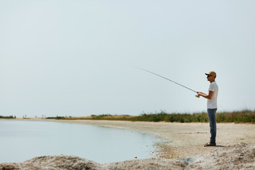 Young man fishing at sea from the shore. fisherman uses spinning