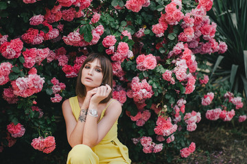 Woman beauty with tattoo on hand near roses in garden.