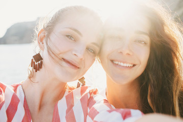 Female friends portrait with sea and mountains on background