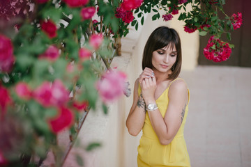 Woman beauty with tattoo on hand near roses in garden.