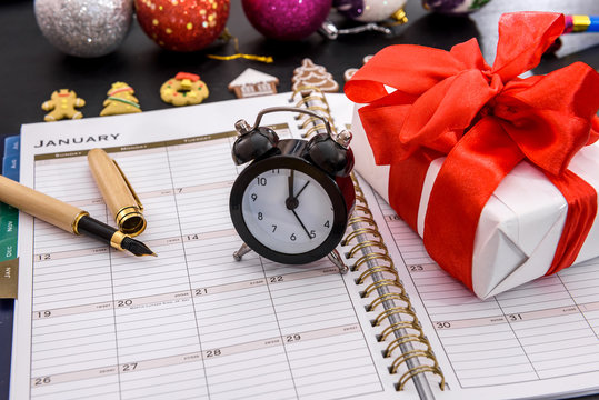 Clock with gift box and notepad on table