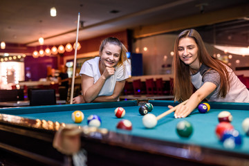 Friends playing billiard aiming on ball in pub