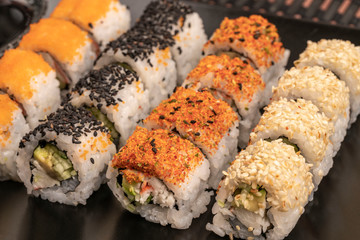 variety of sushi rolls served with soy sauce on table